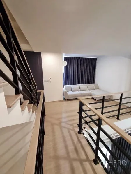 Townhouse for rent - Lounge area with L-shaped sofa by a large curtained window.