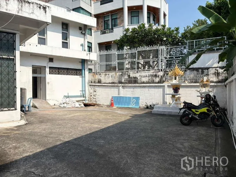Standalone for rent in Khlong Toei, Bangkok - Private outdoor parking courtyard beside neighboring buildings.