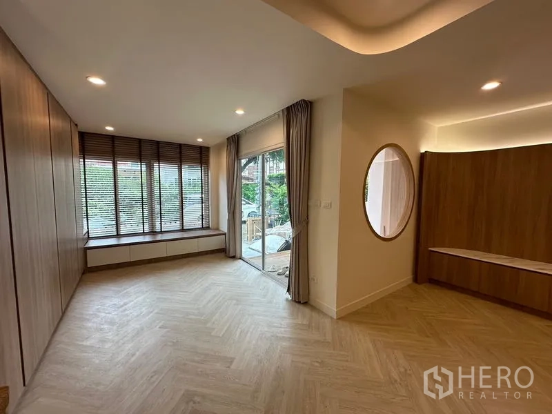 带办公室的家 出租在Khlong Toei, Bangkok - 一层客厅，推拉门通向前庭，窗边长凳与木饰面。