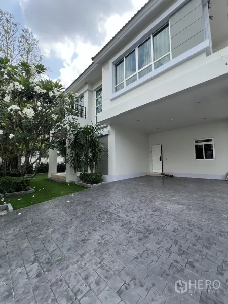 Detached House for rent in Saphan Sung, Bangkok - Angled facade showing spacious driveway, large windows and green lawn.