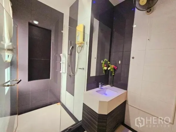 Detached House for rent in Chatuchak, Bangkok - Contemporary bathroom with glass-enclosed shower, dark tiles and a compact illuminated vanity.
