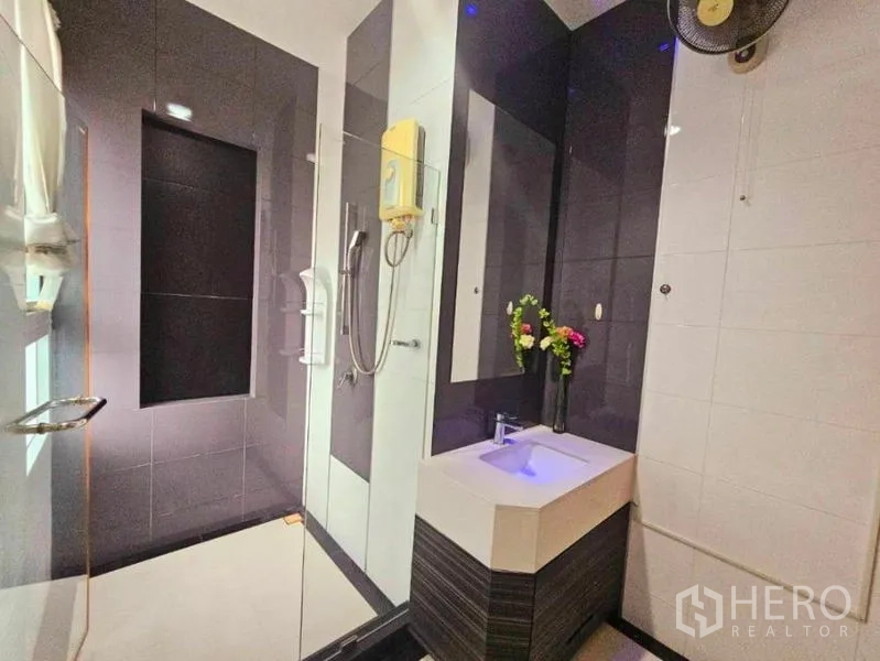 Detached House for rent in Chatuchak, Bangkok - Contemporary bathroom with glass-enclosed shower, dark tiles and a compact illuminated vanity.