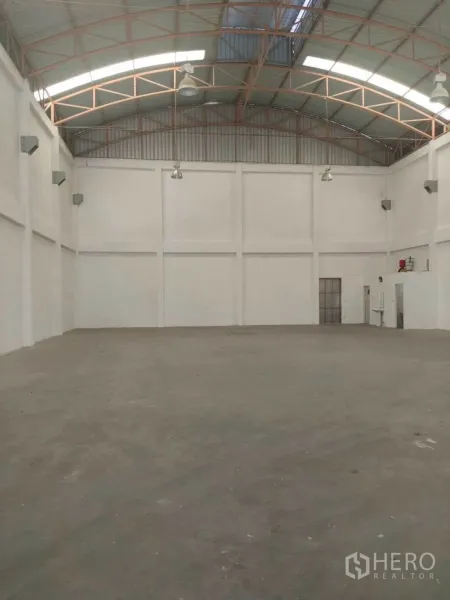 Factory for rent in Phra Samut Chedi, Samut Prakan - Empty warehouse space with high walls, truss roof, and concrete floor.