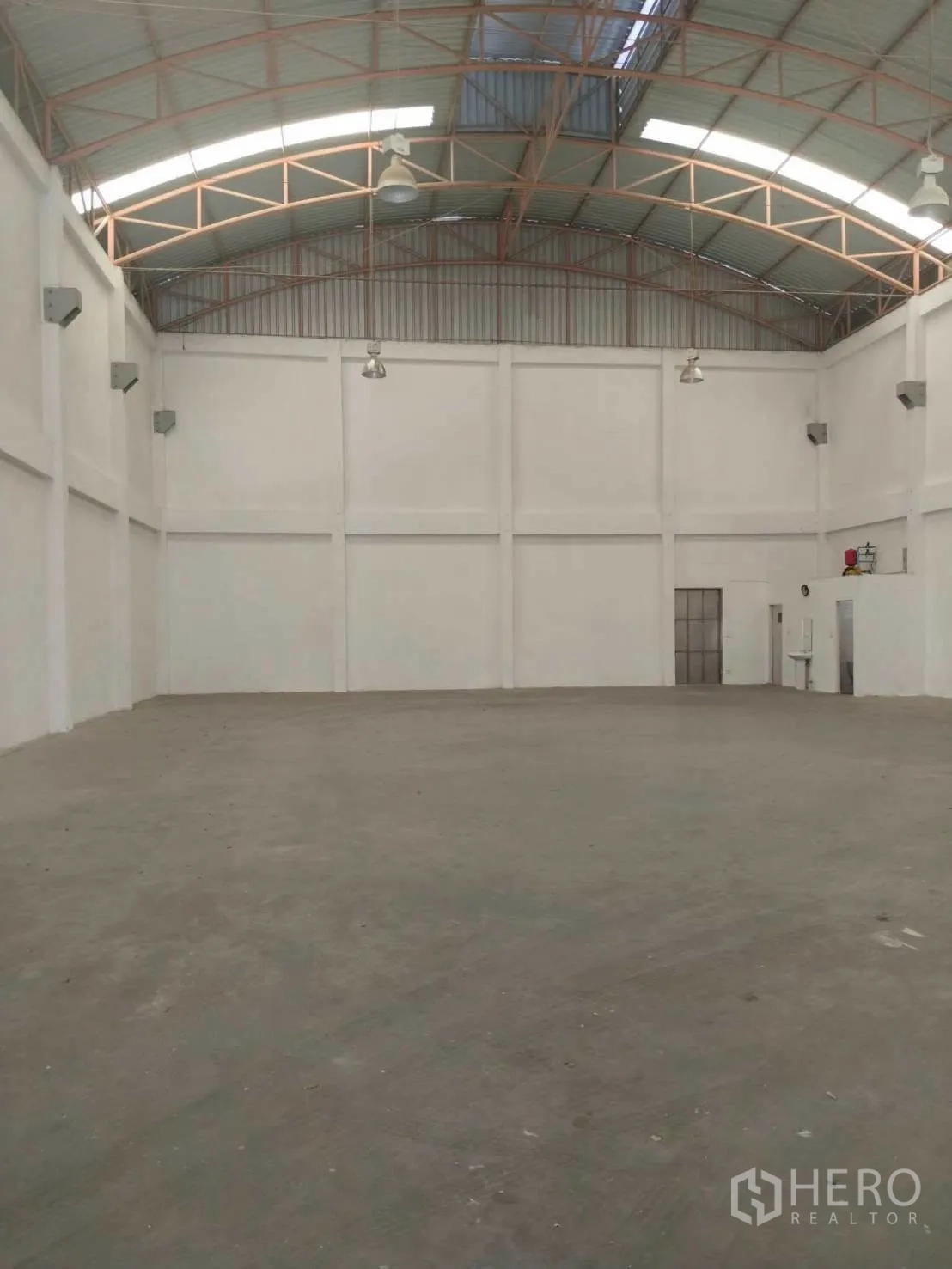 Factory for rent in Phra Samut Chedi, Samut Prakan - Empty warehouse space with high walls, truss roof, and concrete floor.