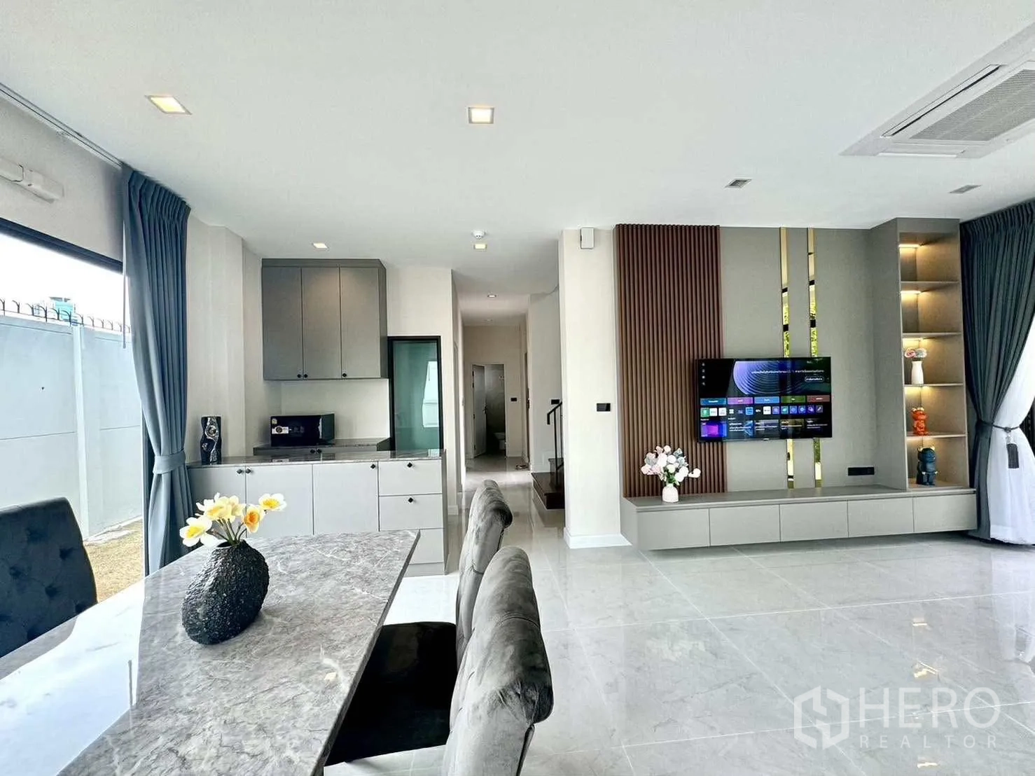 บ้านเดี่ยว for rent in Bang Phli, Samut Prakan - โถงรับแขกและรับประทานอาหารแบบเปิดพร้อมโต๊ะหินอ่อน โซฟา และผนังทีวีบิลท์อิน.