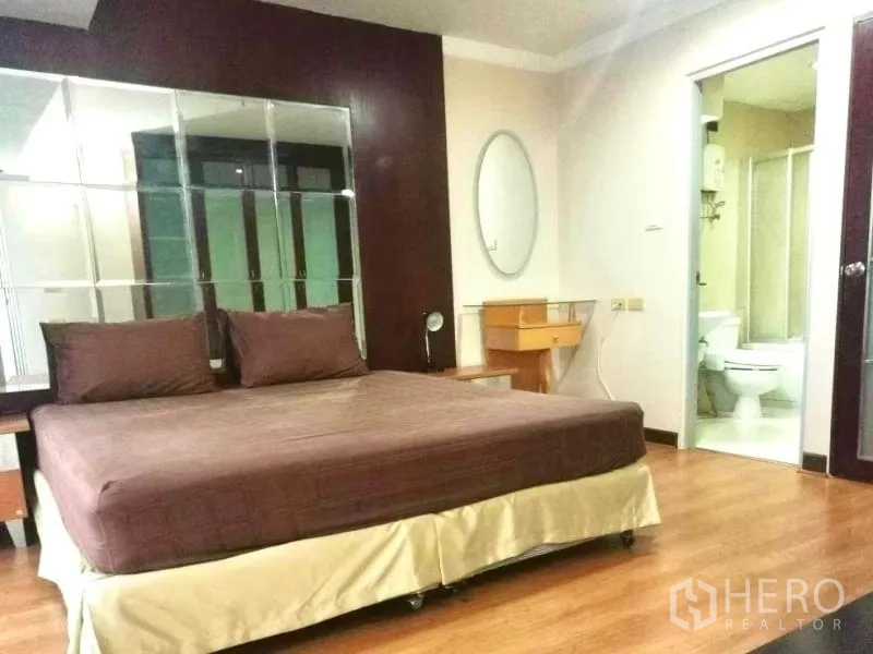 公寓 出租在Khlong Toei, Bangkok - 卧室配大床与镜面墙，滑门连通套内卫浴。