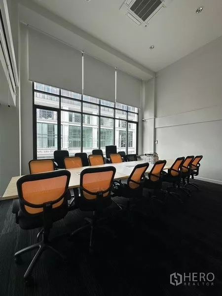 สำนักงานที่บ้าน ให้เช่า - ห้องประชุมเพดานสูง โต๊ะยาว เก้าอี้สีส้ม หน้าต่างกระจกสูง