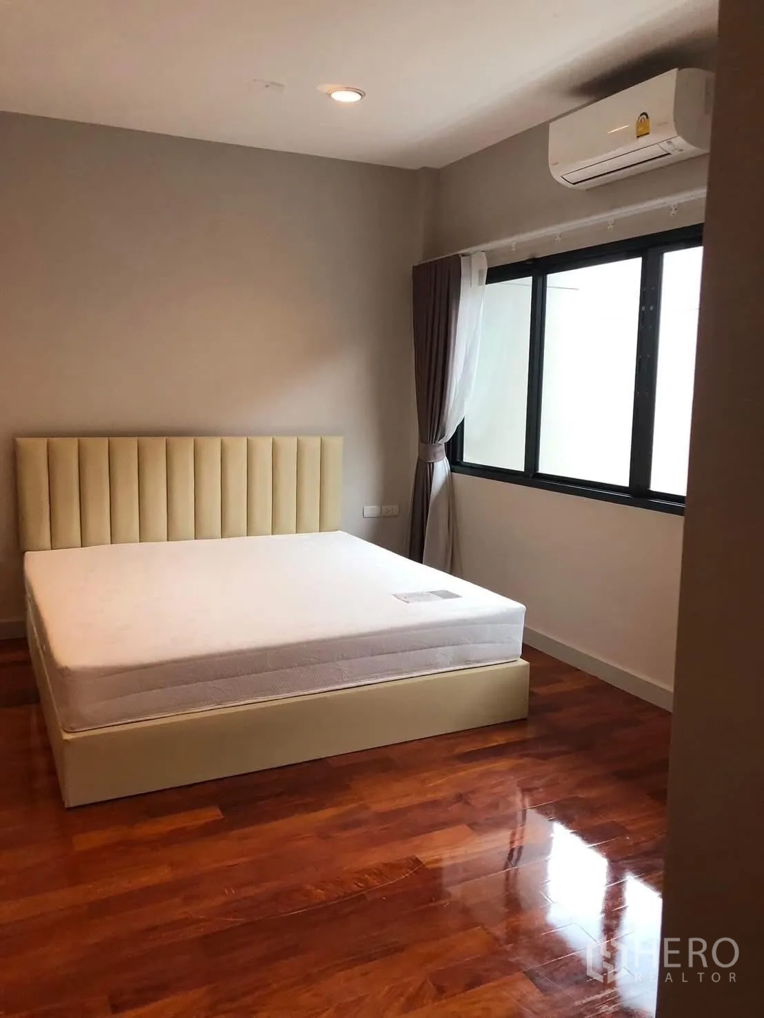 Detached House for rent in Bang Khae, Bangkok - Bright bedroom with upholstered bed, air conditioner, large window and glossy wood floor.