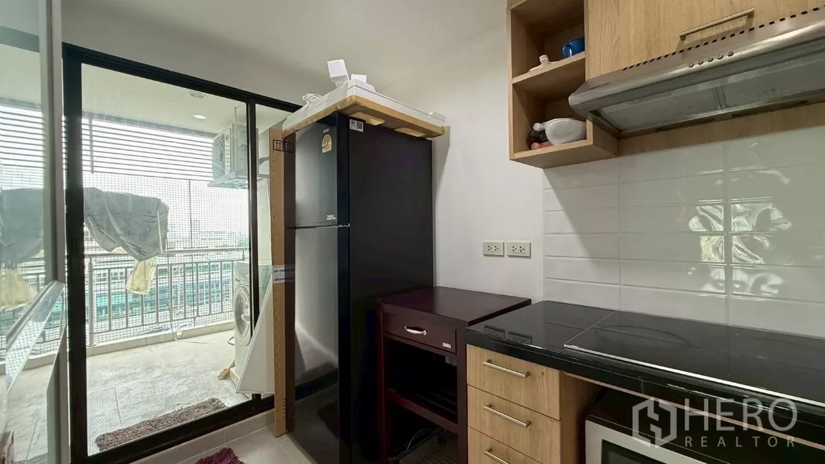 公寓 出售在Yan Nawa, Bangkok - 厨房一角放置冰箱，玻璃门连接洗衣阳台。