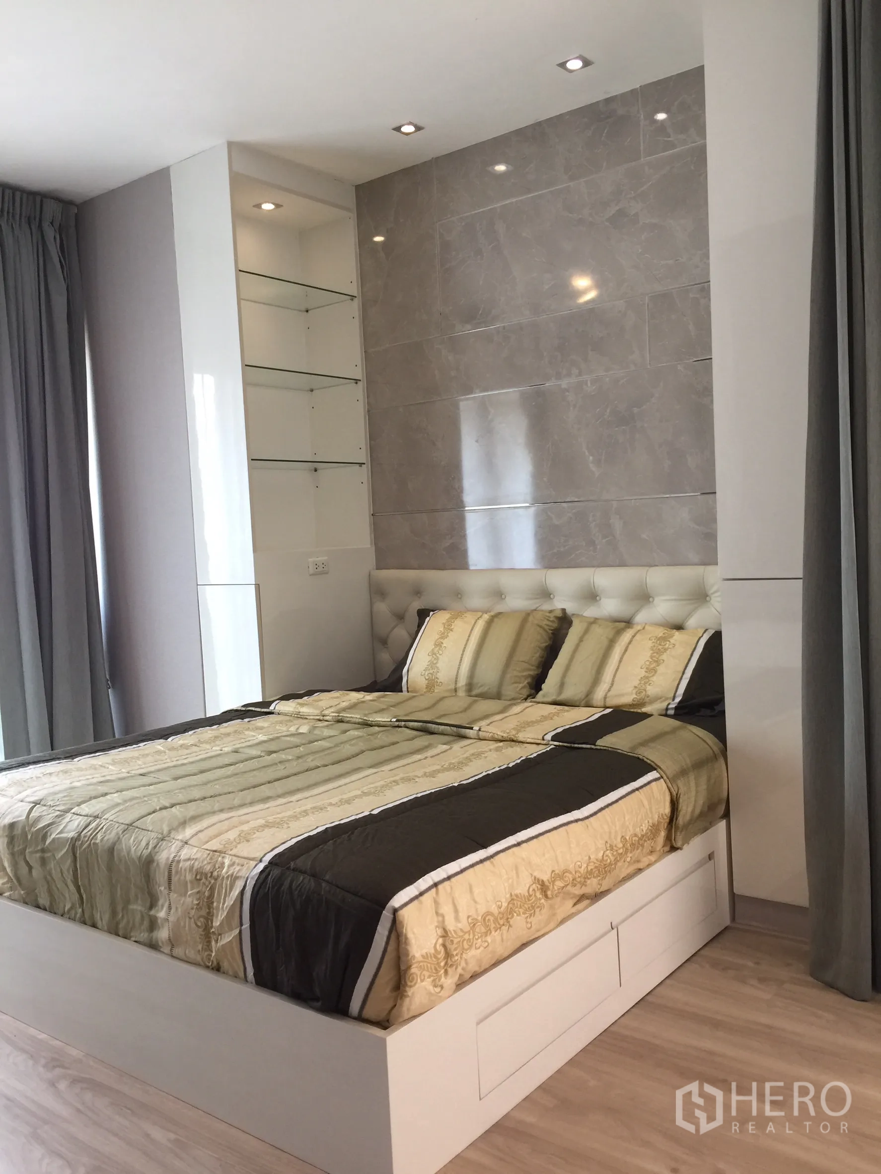 Condominium for rent or sale in Bangkok - Bright bedroom with tufted headboard, marble accent wall and built-in shelving.