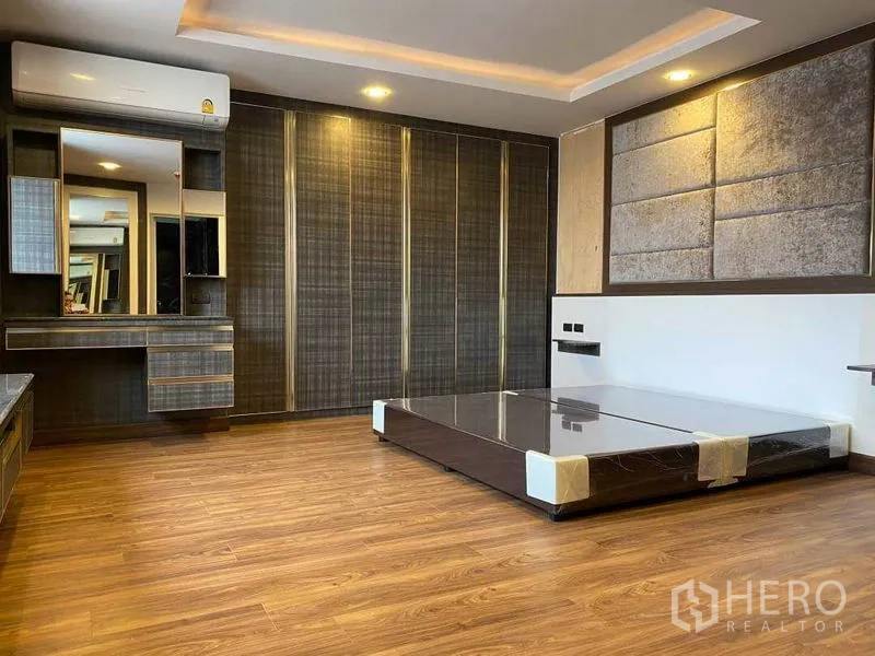 Condominium for rent in Khlong Toei, Bangkok - Large bedroom with low platform bed, dressing area and floor-to-ceiling wardrobes.