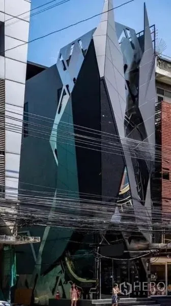 Shophouse for rent in Khlong Toei, Bangkok - Street view of multi-storey shophouse with shard-like facade and glass panels.
