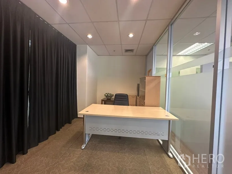 Office Space for rent in Bang Rak, Bangkok - Compact private office with desk, chair, glass partition and blackout curtains.