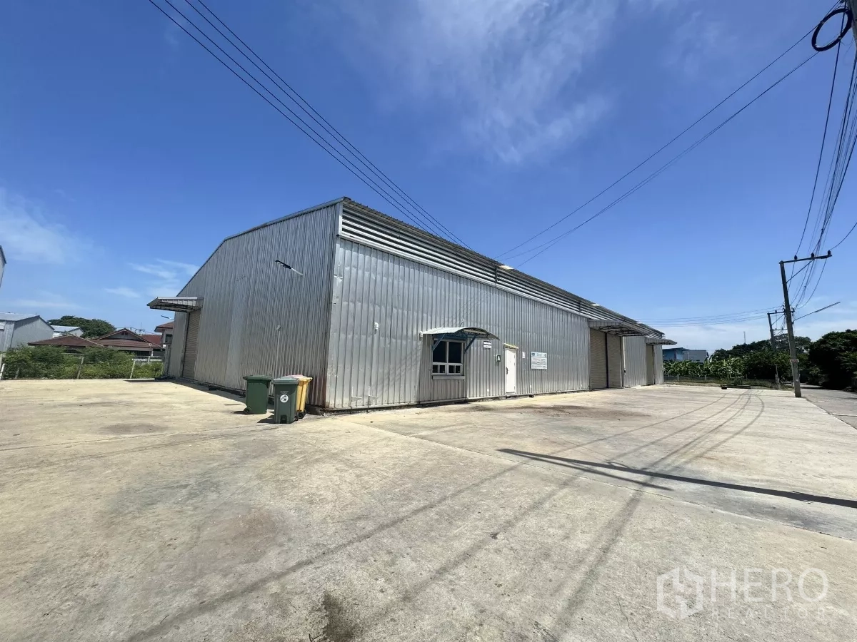 货栈 出租在Bang Lamung, Chon Buri - 仓库侧立面，多个库门与宽大卡车停车及调头区域。