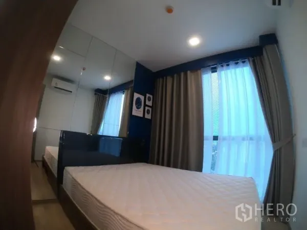 公寓 出租或出售在Watthana, Bangkok - 卧室配镜面衣柜、蓝色点缀墙与落地窗帘，采光柔和