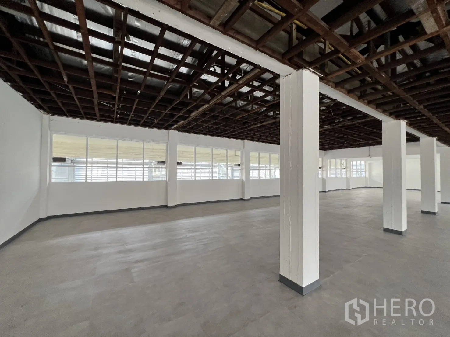办公空间 出租在Watthana, Bangkok - 转角办公区，成排窗户与立柱，便于划分团队区域。