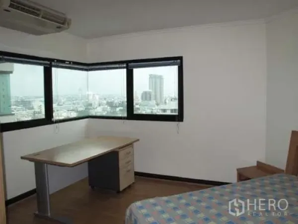 Condominium for rent in Sathon, Bangkok - Corner bedroom with wraparound windows, a work desk and wide city skyline views.