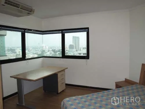 Condominium for rent in Sathon, Bangkok - Corner bedroom with wraparound windows, a work desk and wide city skyline views.