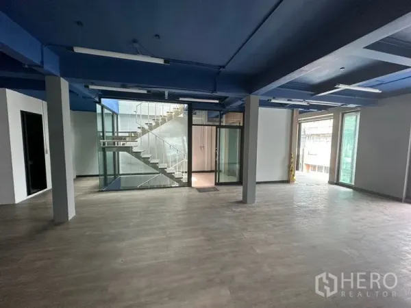 办公空间 出租在Watthana, Bangkok - 开放式写字楼，蓝色天花与木纹地板，中央为玻璃楼梯井。