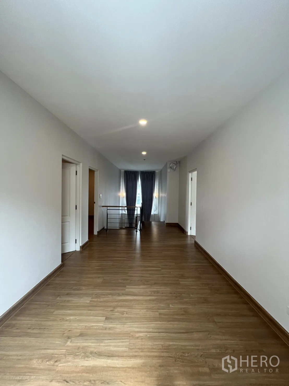 独栋房屋 for rent in Lat Krabang, Bangkok - 长形楼层走廊，木地板与照明通向楼梯栏杆。