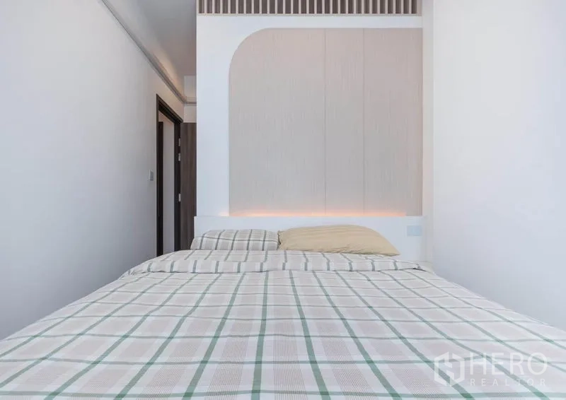 公寓 出租在Bang Na, Bangkok - 卧室配拱形床头背景墙，暖色隐藏灯带与格纹床品。