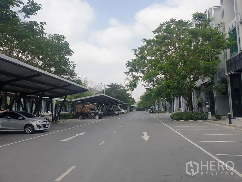 Home Office for rent - Wide internal road with shaded parking structures and mature trees.