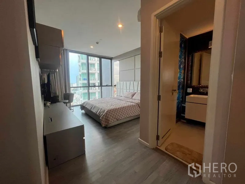 Condominium for rent in Khlong Toei, Bangkok - Bedroom corridor to ensuite bathroom with gray wood floors and large windows.