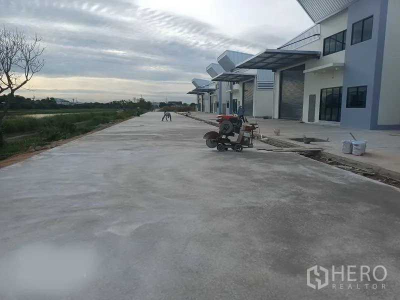 Factory for rent in Bang Phli, Samut Prakan - Wide truck-friendly concrete driveway in front of warehouse row with covered loading canopies.