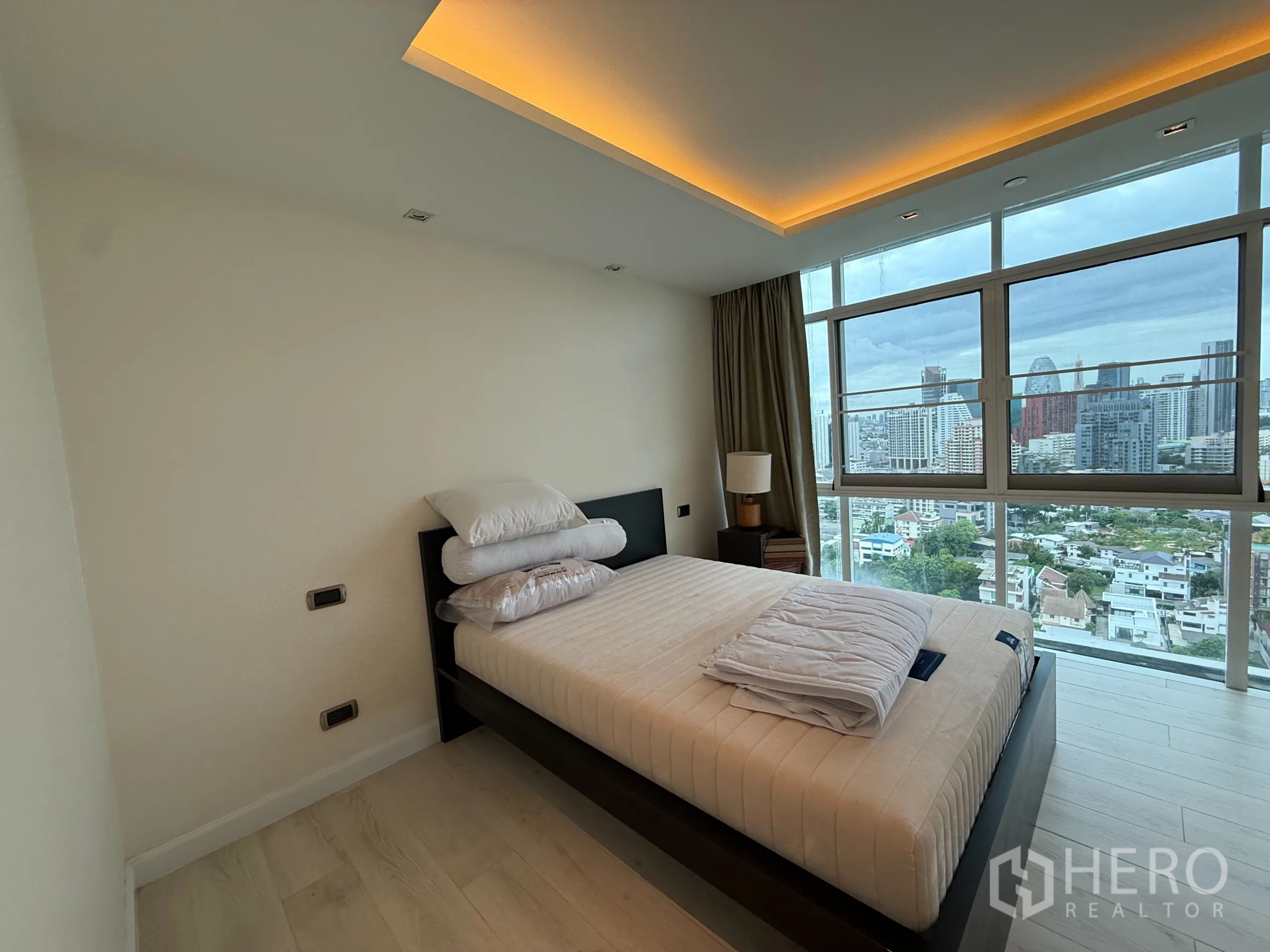 Condominium for rent in Phaya Thai, Bangkok - Second bedroom with bed by floor‑to‑ceiling windows overlooking Bangkok.