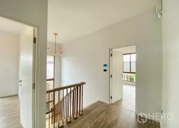 Detached House for sale in Bang Kapi, Bangkok - Upper hallway with wooden handrail and doors leading to bedrooms.