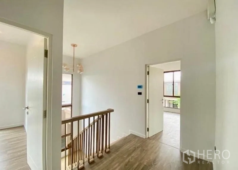 Detached House for sale in Bang Kapi, Bangkok - Upper hallway with wooden handrail and doors leading to bedrooms.