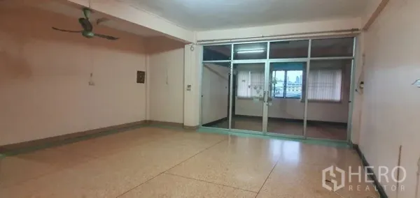 Warehouse for rent in Bang Kho Laem, Bangkok - Spacious room with terrazzo floor, ceiling fan, and sliding glass partition.