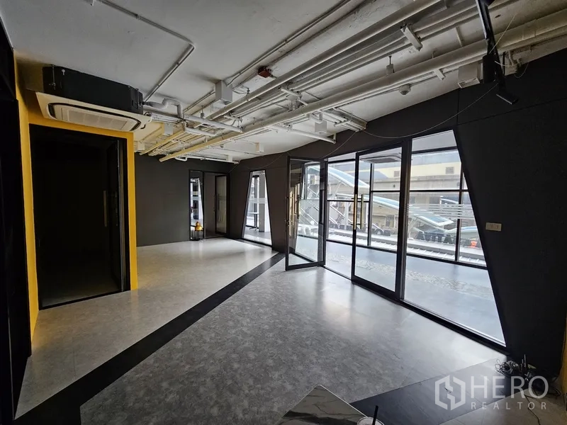 Retail Space for rent - Corner retail space with floor-to-ceiling windows and folding glass doors allowing natural light.