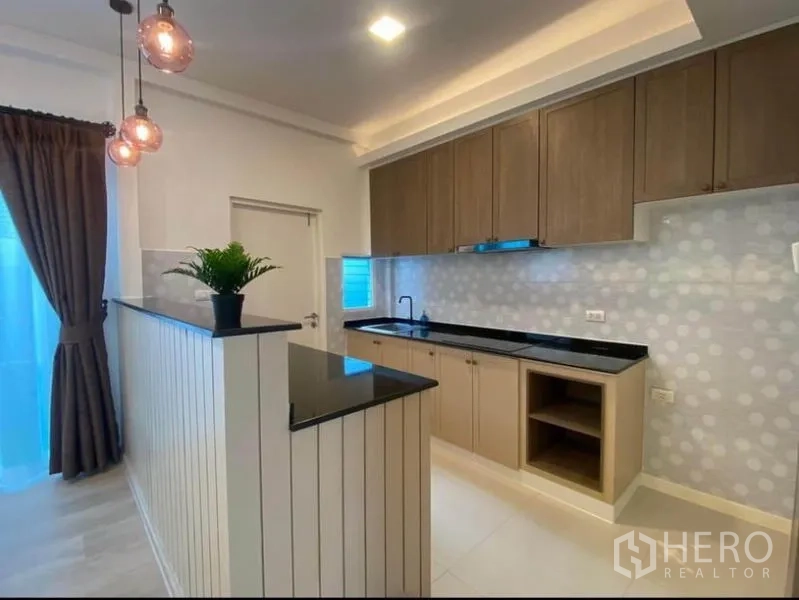 Townhouse for rent in Prawet, Bangkok - Open kitchen with breakfast bar, wood cabinetry and dotted tile backsplash.