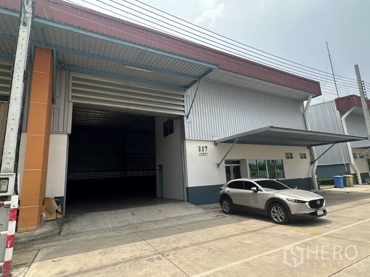 โรงงาน ให้เช่าในBang Phli, Samut Prakan - ด้านหน้าอาคารโรงงาน มีกันสาด พื้นที่จอดรถ และประตูม้วนเปิด