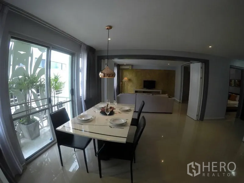 Condominium for rent in Watthana, Bangkok - Marble-top dining table under a copper pendant light next to balcony plants.