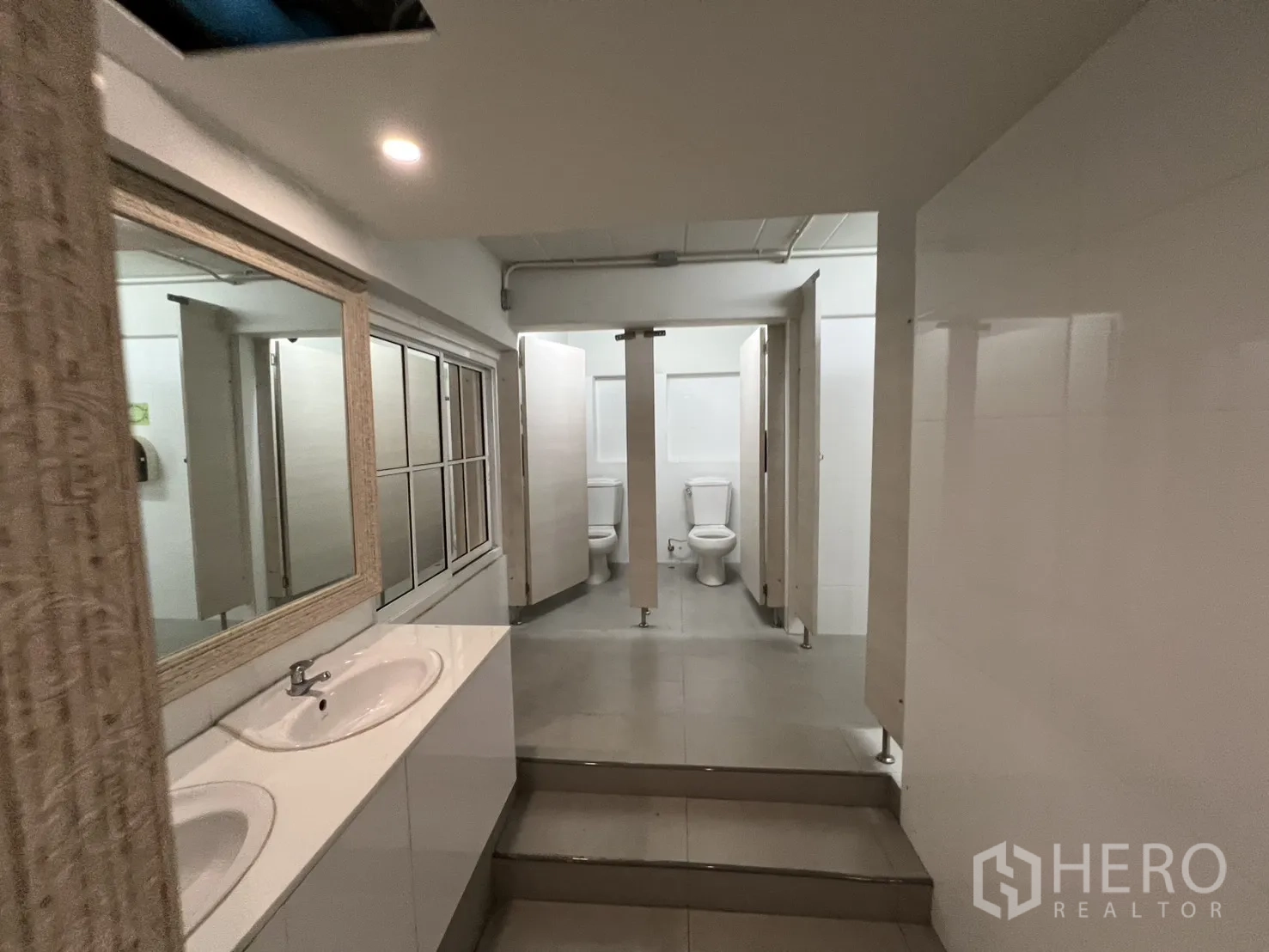 Shophouse for rent in Bang Rak, Bangkok - Clean restroom area with multiple toilet stalls and double vanity sinks.