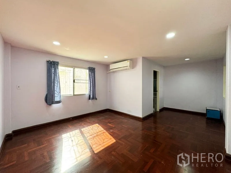 Townhouse for rent or sale in Suan Luang, Bangkok - Spacious bedroom with parquet floor, air conditioning and ensuite doorway