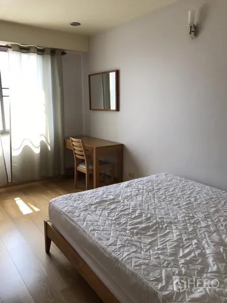 公寓 出租在Watthana, Bangkok - 卧室内木质床，窗边书桌与纱帘。