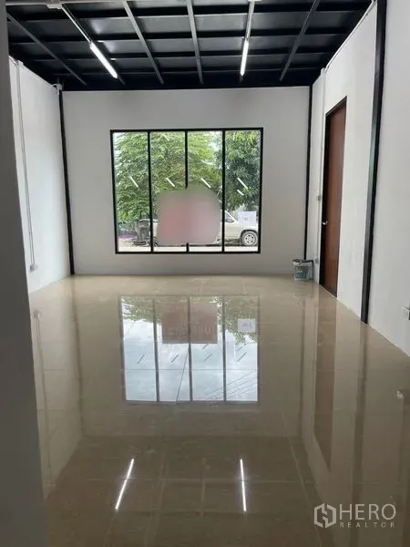Warehouse for rent or sale in Lam Luk Ka, Pathum Thani - Ground-floor office room with glossy tiled floor, large window and white walls overlooking the front yard.