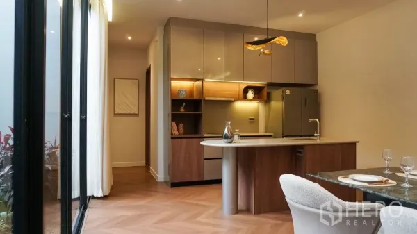 Detached House for rent or sale in Bang Kapi, Bangkok - Contemporary Western kitchen with island, wood cabinetry and warm under-cabinet lighting.