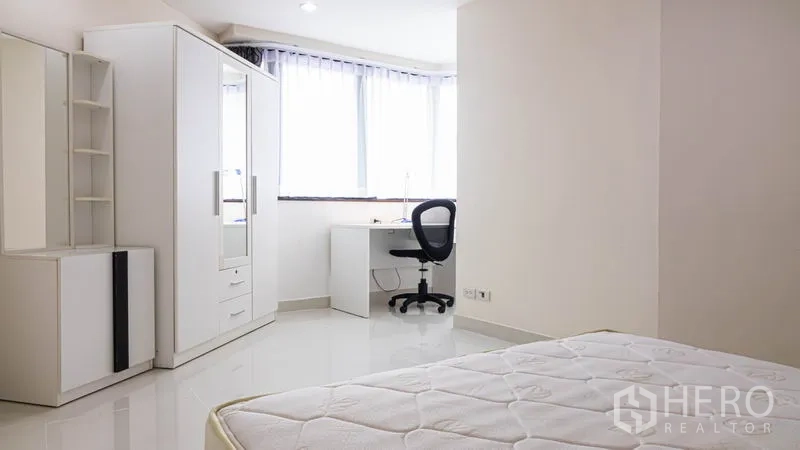 Condominium for rent or sale in Khlong Toei, Bangkok - Bright white bedroom with wardrobe, study desk and corner window.