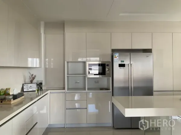 Apartment for rent in Sathon, Bangkok - Modern glossy kitchen with built‑in cabinets and double‑door fridge.