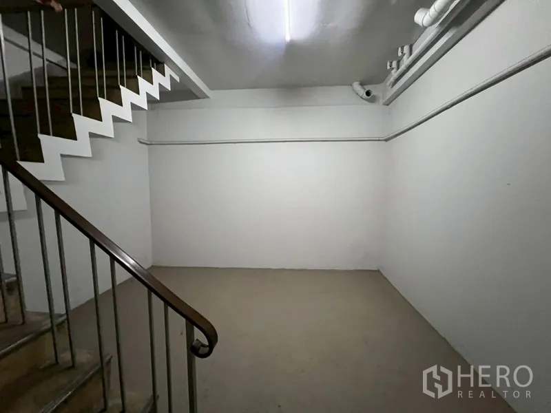 Shophouse for rent in Phra Khanong, Bangkok - Interior stairwell with metal handrail and white walls leading between floors.