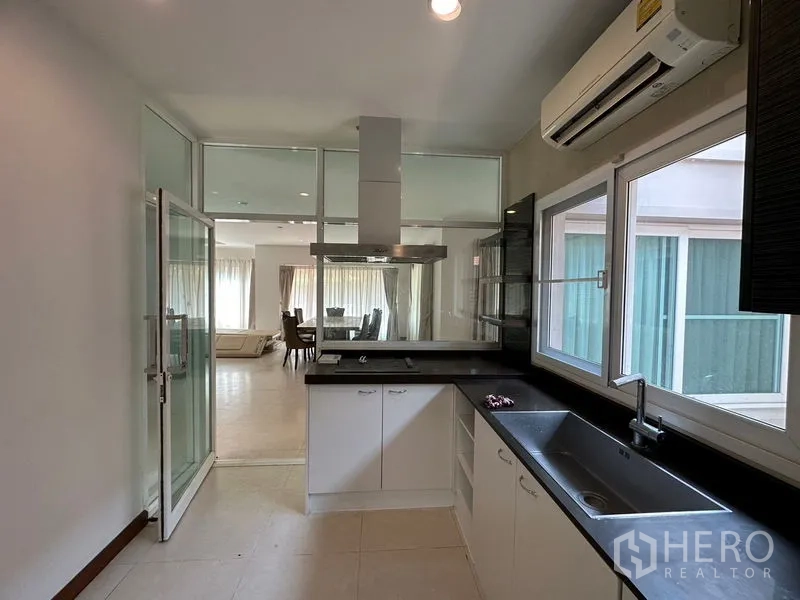 独立式住宅 出租或出售在Pak Kret, Nonthaburi - 厨房通过玻璃隔断望向客餐厅，配排烟机。