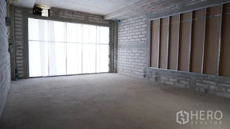 Retail Space for rent in Khlong Toei, Bangkok - Vacant retail space with natural light from full-width glass and an unfinished screed floor.