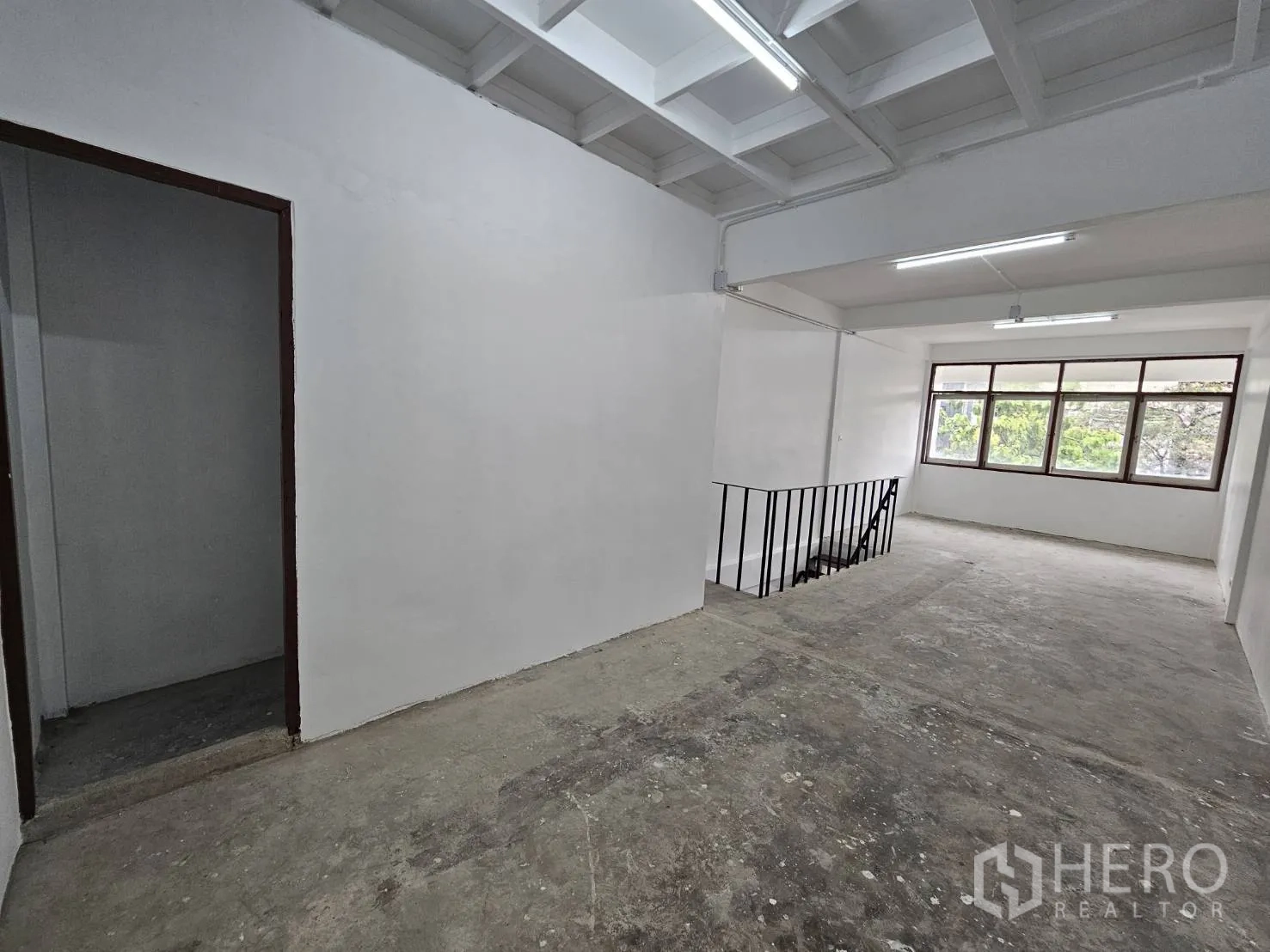 Home Office for rent in Khlong Toei, Bangkok - Open studio floor with doorway to a side room and greenery views.