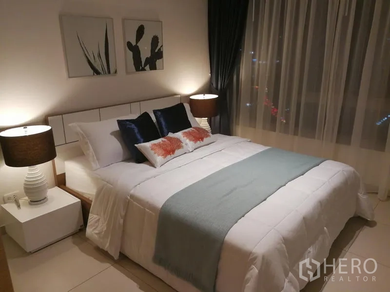 公寓 出租或出售在Watthana, Bangkok - 夜晚卧室，大窗与床头灯，窗外城市灯光璀璨。