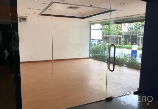 Retail Space for rent in Bang Rak, Bangkok - Bright ground-floor retail unit with floor-to-ceiling glass storefront, wood flooring, recessed lights, and street-facing window near transit.
