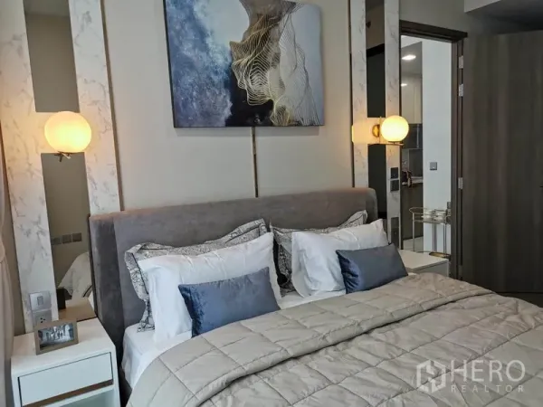 Condominium for rent in Watthana, Bangkok - Cozy bedroom with upholstered bed, pendant lamps, and contemporary artwork above the headboard.